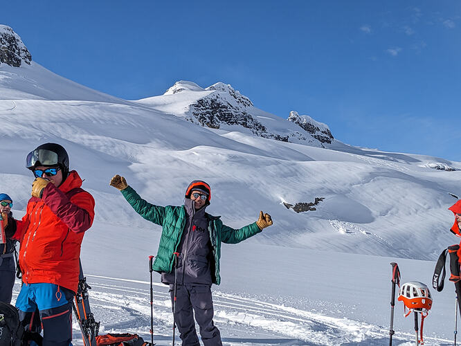 skier taking a break at foot of large snowy slope wearing a puffy jacket. photo J. Buckley