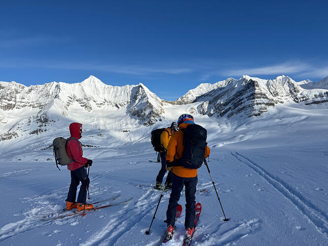 three skiers looking at impressive snow covered peaks